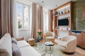 Una sala de estar moderna con un sofá, sillones, una mesita de centro y un televisor.