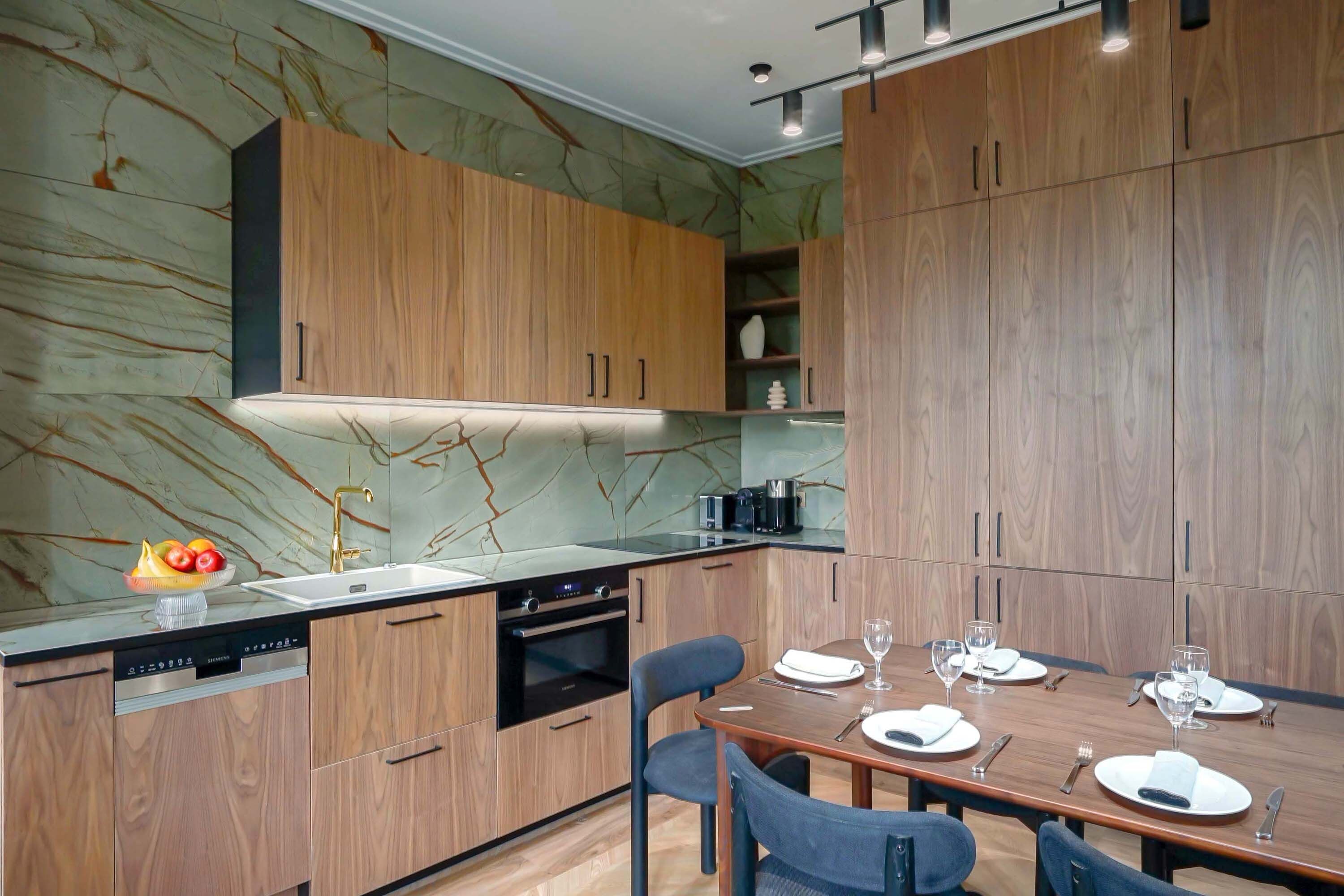 A modern kitchen with wooden cabinets, a built-in oven, and a dining area with a table set for four.