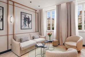 Un salon moderne avec un canapé, des fauteuils, une table basse et un tableau accroché au mur.