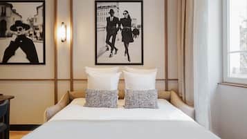 A hotel room with a bed, two pillows, a nightstand, a lamp, and two framed pictures on the wall.