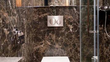 Une salle de bain moderne avec un meuble-lavabo en marbre, des toilettes et une douche séparée par une paroi en verre.