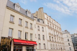 Un edifici de diversos pisos amb una cafeteria anomenada "Cafe de la Porte des Sablons" a la planta baixa.