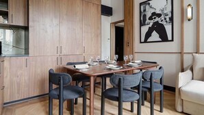 A dining area with a wooden table set for four, surrounded by chairs, and a sofa in the corner.