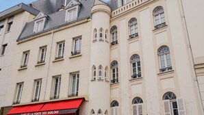 A multi-story building with a red awning labeled "CAFÉ DE LA PORTE DES SAUBONS" and a corner turret with arched windows.