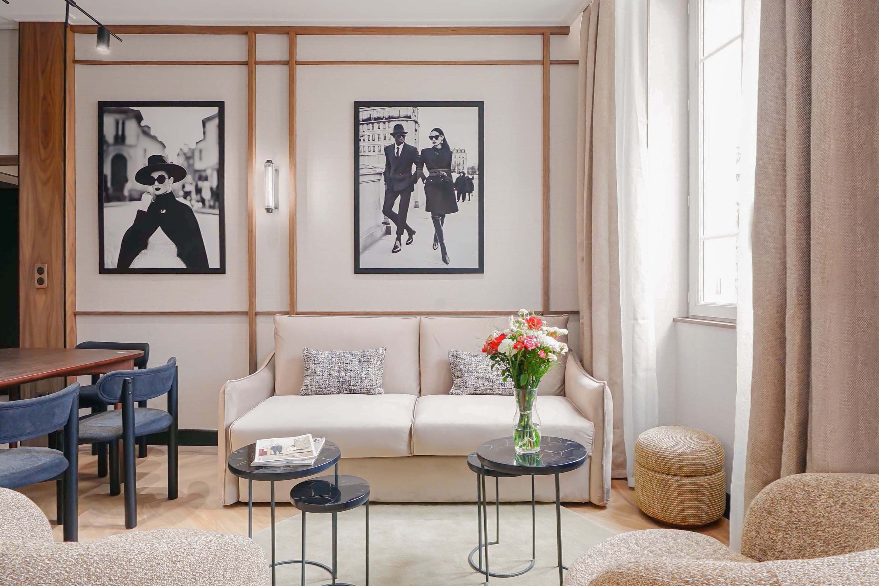 Un salon moderne avec un canapé, deux tables d’appoint, une table basse et un vase de fleurs.