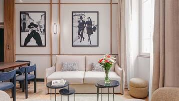 Un salon moderne avec un canapé, deux tables d’appoint, une table basse et un vase de fleurs.