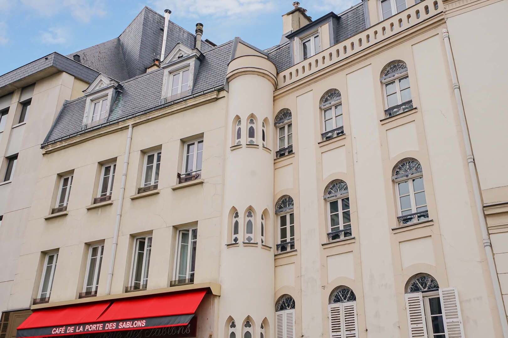 A multi-story building with a red awning labeled "CAFÉ DE LA PORTE DES SAUBONS" and a corner turret with arched windows.