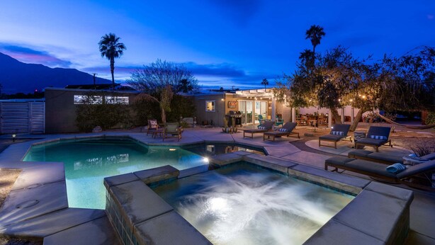 Ein Swimmingpool mit Whirlpool, Liegestühlen und einer Terrasse mit Gartenmöbeln.