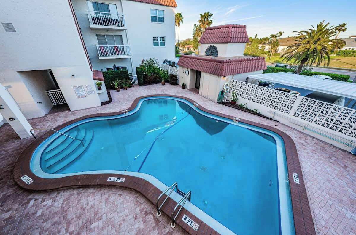 A swimming pool with a curved edge, surrounded by a brick patio.