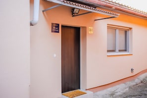 A single-story building with a wooden door and a window. There are two signs: one indicating the building is an apartment and another with a number. - Peaceful Nest In City Center (Zagreb)