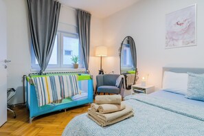 A hotel room with a bed, a chair, a bedside table with a lamp, a mirror, and a window with curtains. - Peaceful Nest In City Center (Zagreb)