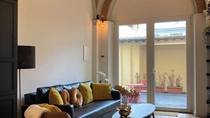 Ein Wohnzimmer mit einer schwarzen Ledersofa, einem runden Couchtisch und Holzdielen.