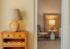 A wooden nightstand with a lamp, a wicker chair, and a striped wall in a hotel room.