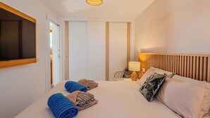 Una habitación de hotel con cama, televisión, lámpara y toallas.
