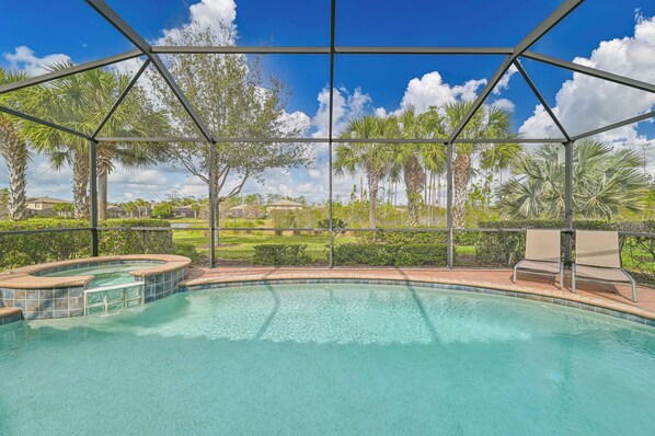 Piscina con vistas a palmeras y casas, rodeada por una valla metálica.