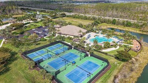 Vista aérea de un complejo turístico con múltiples canchas de tenis, una piscina y una zona frente a la playa.