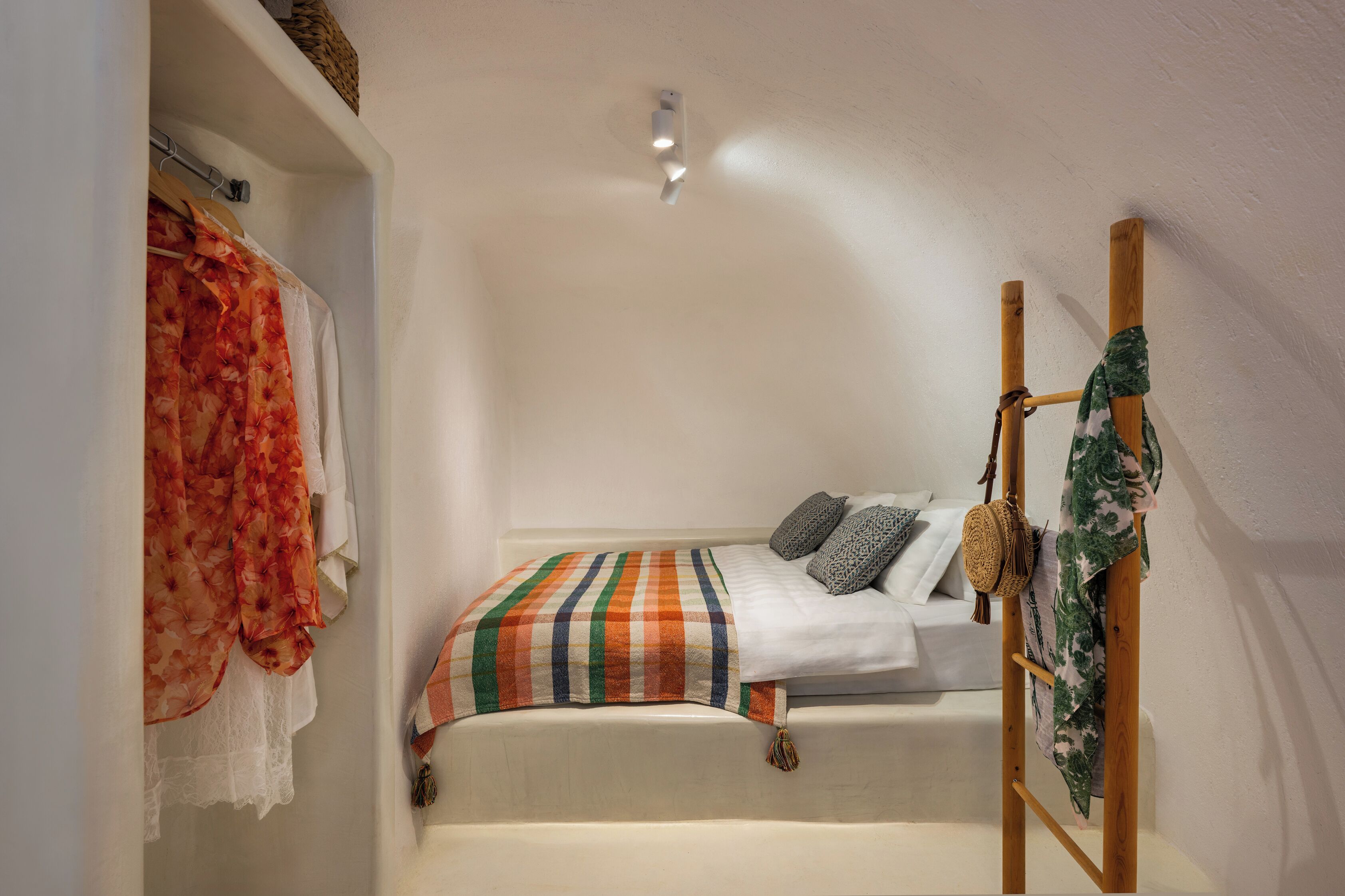 A small, cozy bedroom with a single bed, a wooden ladder, and a hanging basket.