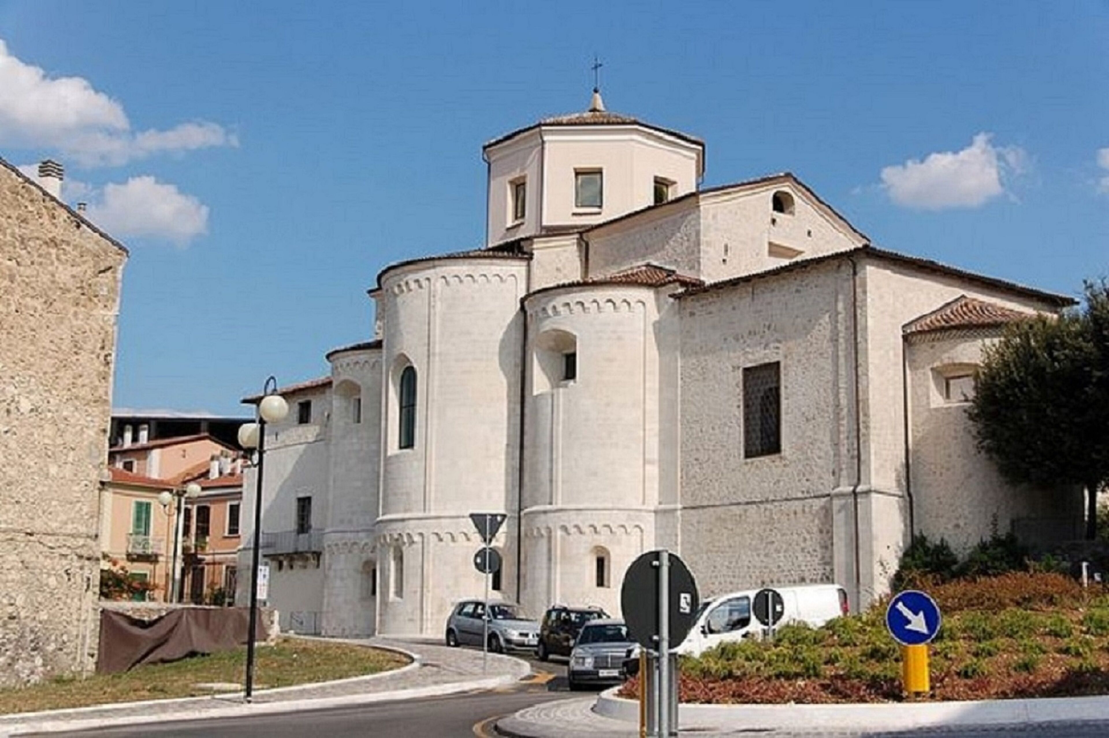 A church with a bell tower and a round building with arched windows.