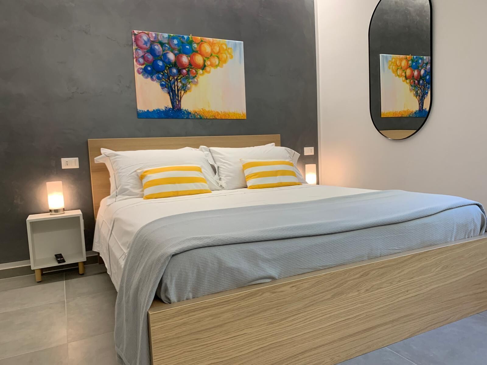 Une chambre à coucher moderne, avec un lit, des tables de chevet et un miroir fixé au mur.