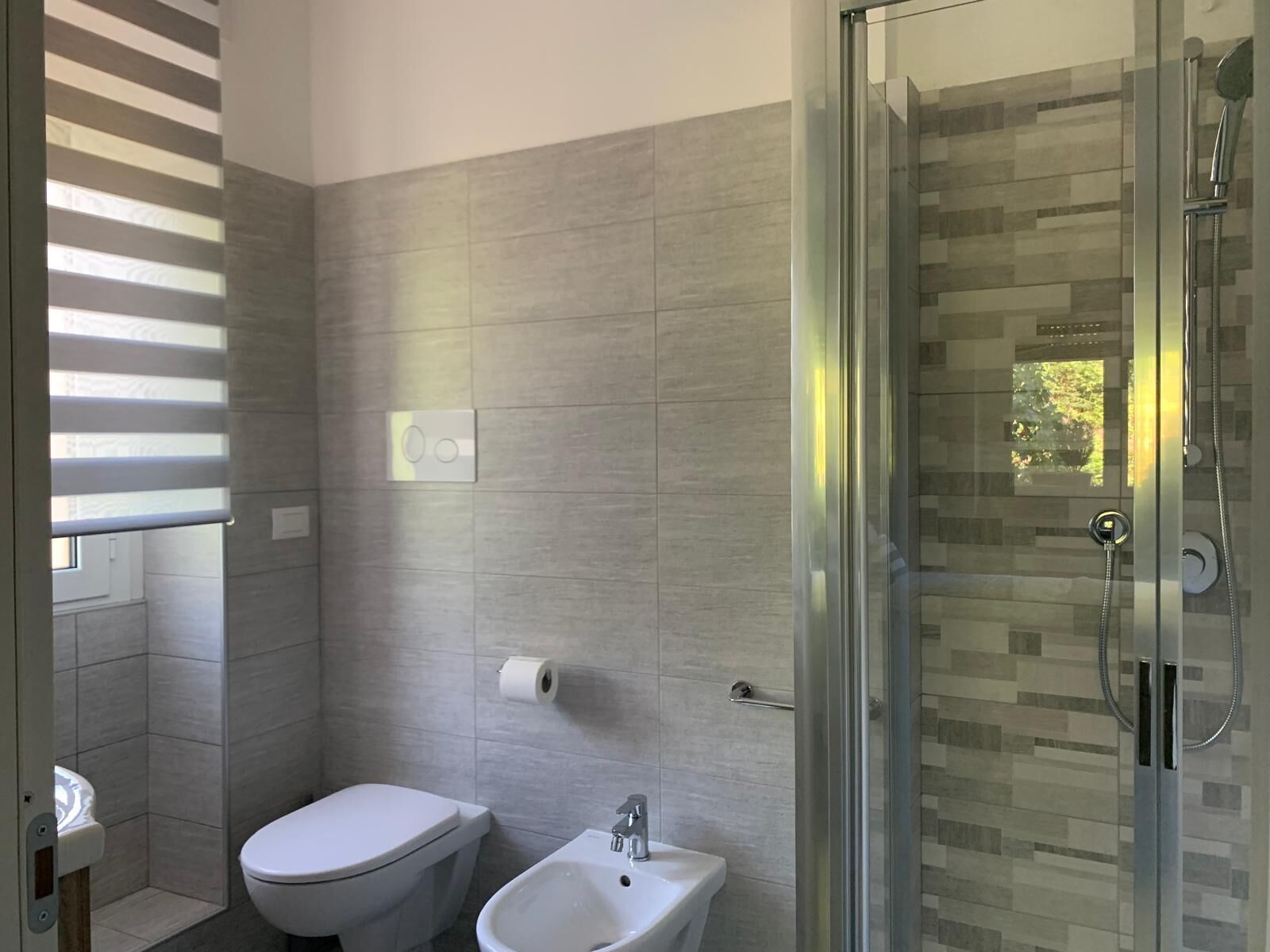A modern bathroom with a toilet, bidet, and glass-enclosed shower.