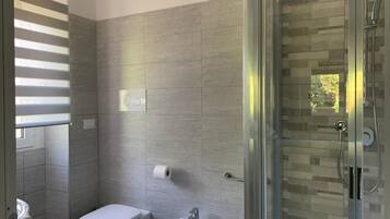 A modern bathroom with a toilet, bidet, and glass-enclosed shower.