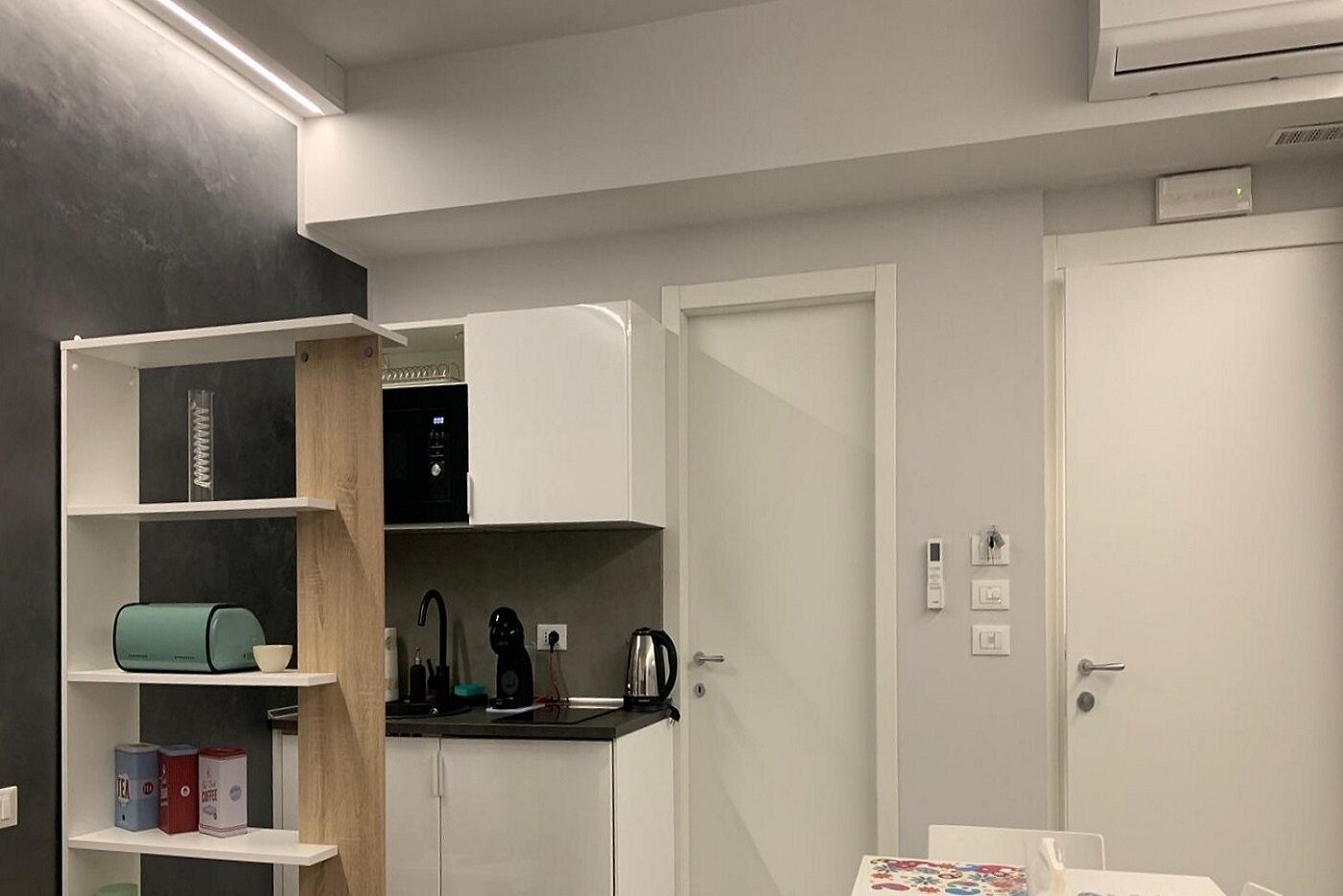 A compact kitchenette with a coffee machine, kettle, and tea maker on the countertop.