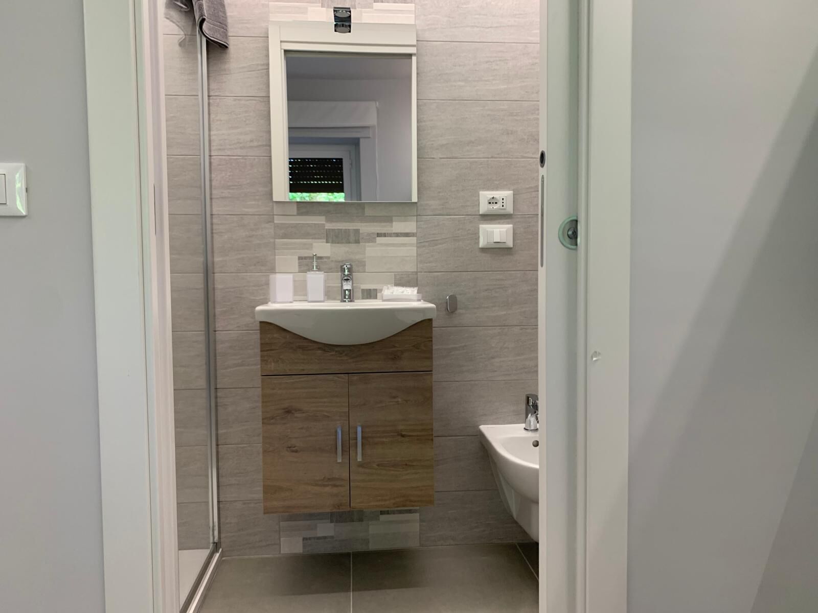 A modern bathroom with a white sink, wooden cabinets, and a mirror above the sink.
