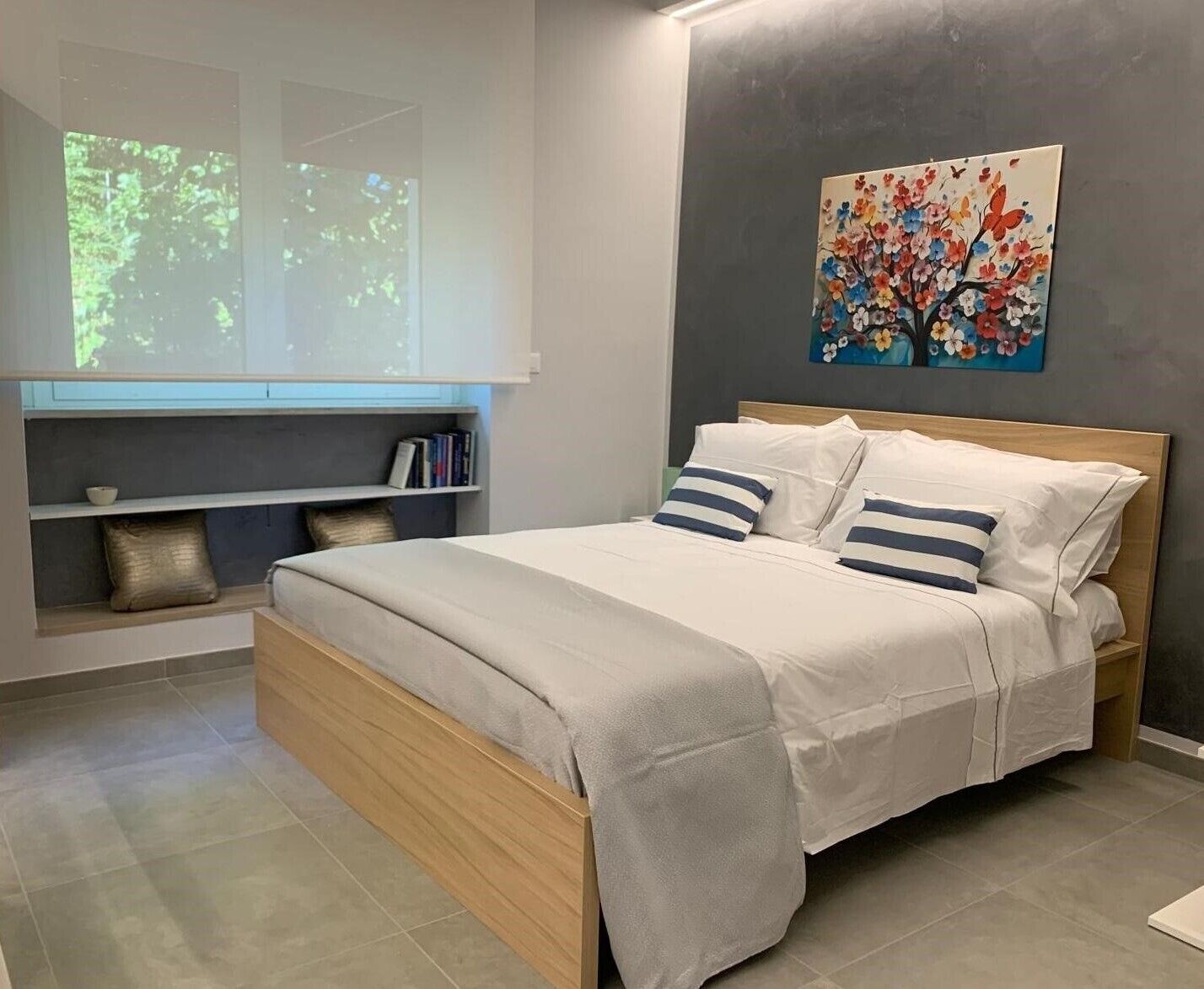 A modern bedroom with a bed, a bookshelf, and a projector screen displaying a nature scene.