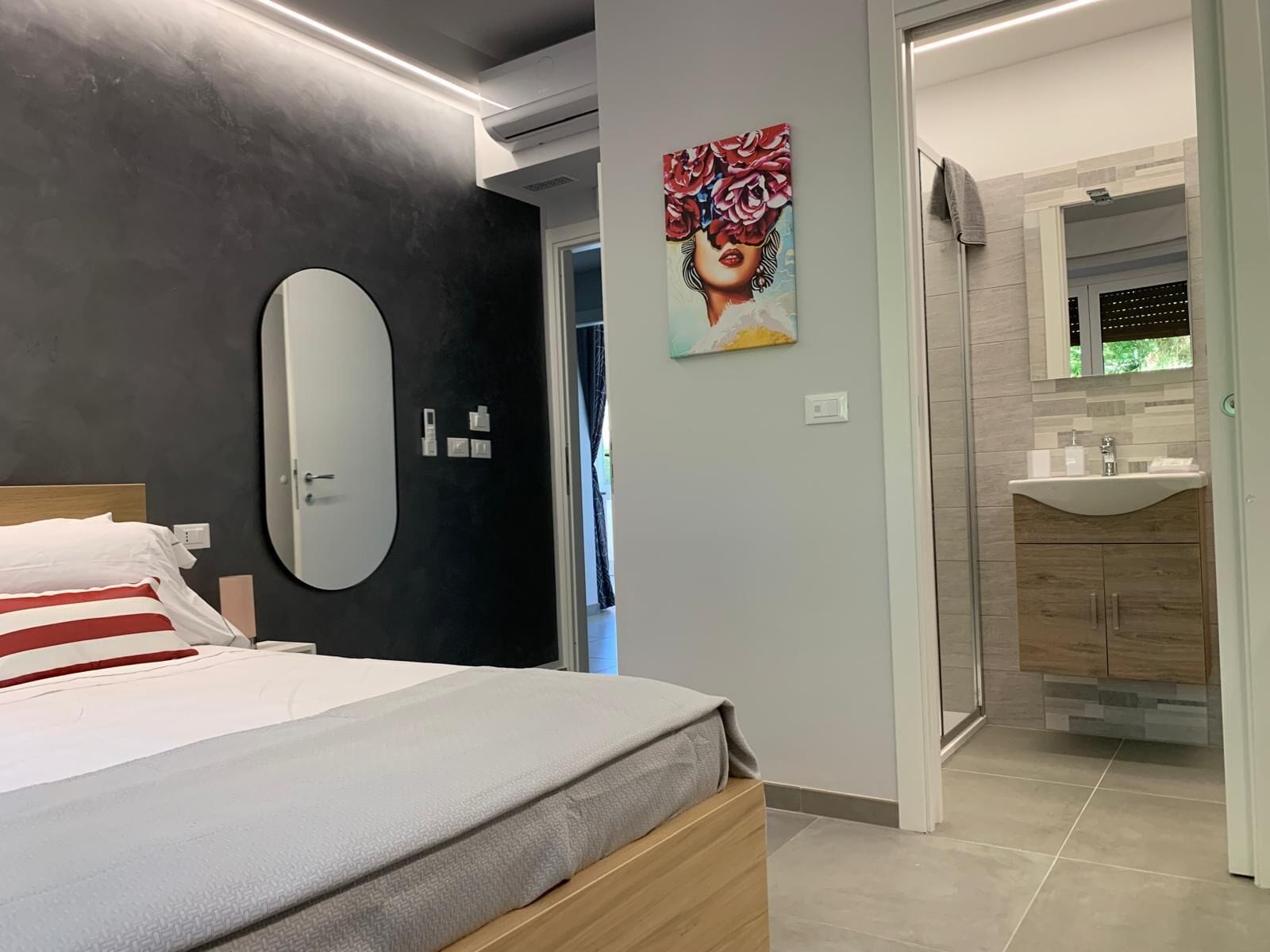 Ein modernes Schlafzimmer mit einem Bett, einem großen Spiegel und einem Gemälde an der Wand.