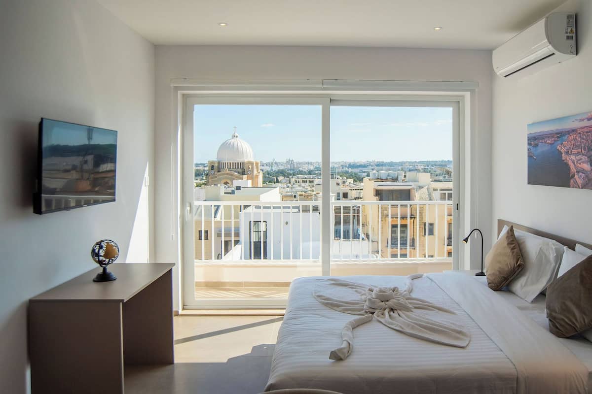 Una camera da letto con un letto grande, vista sulla città attraverso una porta scorrevole e un quadro appeso al muro.