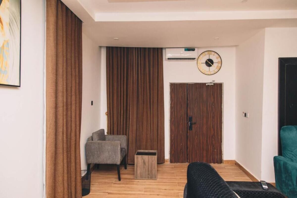 Ein modernes Wohnzimmer mit einer Couch, einem Sessel, einem Holzschrank und einer großen Wanduhr.