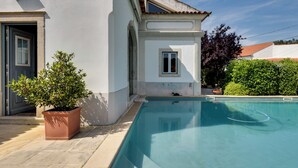 Piscina ao lado de um edifício branco com telhado telhado e um vaso de planta.