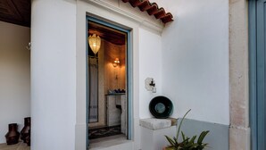 Uma porta com moldura azul, um vaso de planta e um aplique na parede.