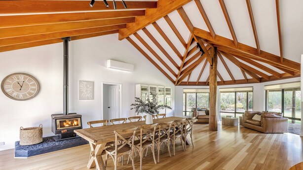 Une pièce spacieuse avec une table à manger en bois, des chaises, une grande fenêtre et une cheminée.