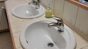 Un baño con dos lavamanos, un espejo y una ventana con persianas.