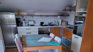 Una cocina funcional con una mesa, sillas, refrigerador, estufa y microondas.