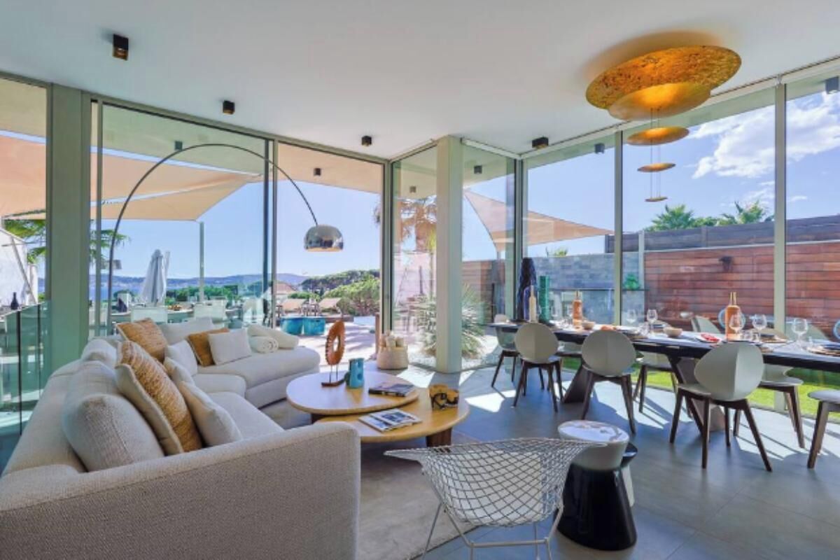 A modern living room with a sofa, coffee table, and dining area with chairs and a table set for a meal.