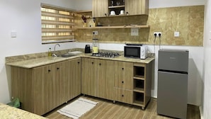 Una cucina compatta con mobili in legno, piano cottura a gas, forno a microonde e frigorifero.