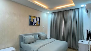Una camera da letto moderna con un letto grande, un comodino, un tavolino e un condizionatore d'aria a muro, oltre a un tappeto decorativo.