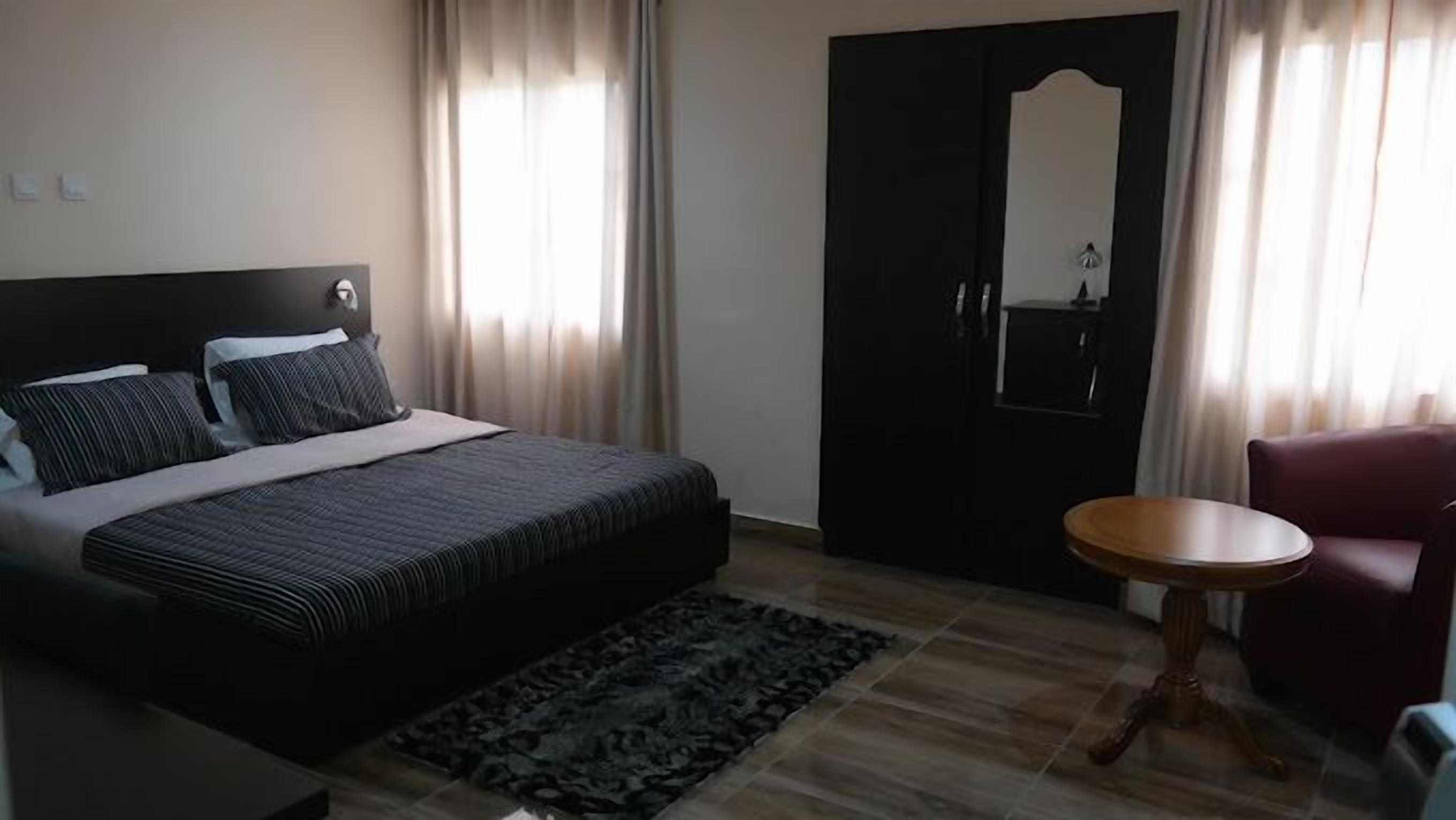 A bedroom with a bed, a round table, a chair, and a wardrobe.