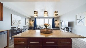 A modern kitchen with a large island, pendant lights, and artwork on the walls.