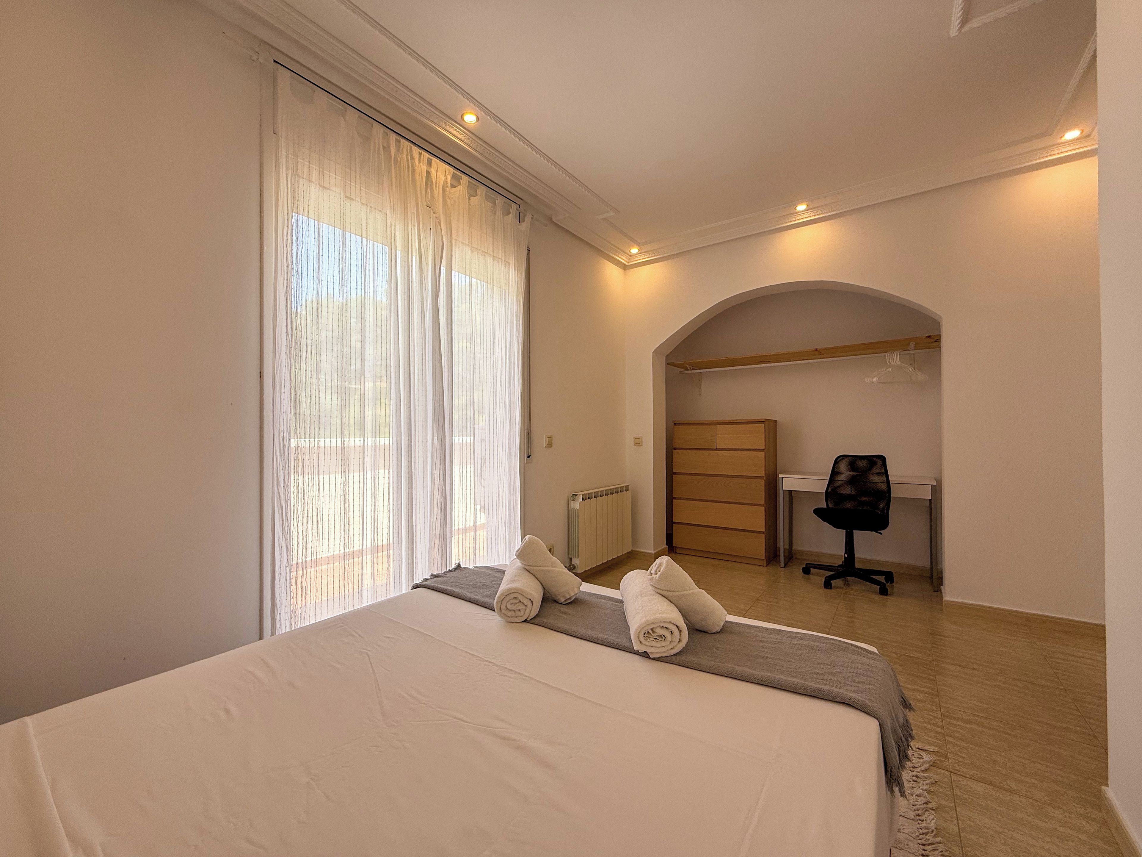 A hotel room with a bed, a desk, and a chair.