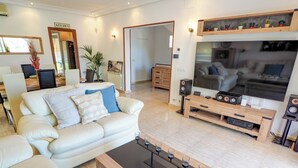 Een moderne woonkamer met een witte bank, een salontafel, een televisie en een houten tv-meubel.