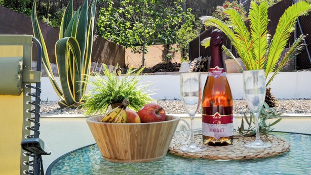 Een glazen tafel met een fles roséwijn, een fruitschaal en een glas water.