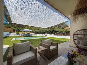 A patio area with wicker furniture, a pool, and a white canopy. - Villa Claudia by Hello Homes Sitges (Sitges)