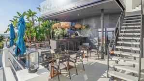 Ein moderner Außenbereich zum Essen mit Glasveranda, einer Bar und einer Treppe.