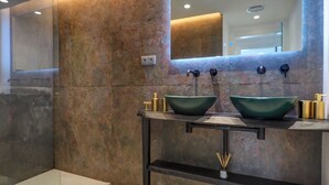 Ein modernes Badezimmer mit zwei grünen Waschbecken, einem Spiegel darüber und einem Ablagefach mit Pflegeprodukten.
