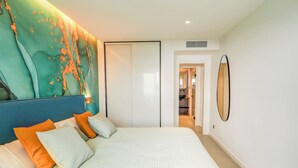 Ein modernes Schlafzimmer mit einem großen Bett, einem Kopfteil mit strukturierter Optik und einem wandmontierten Spiegel.
