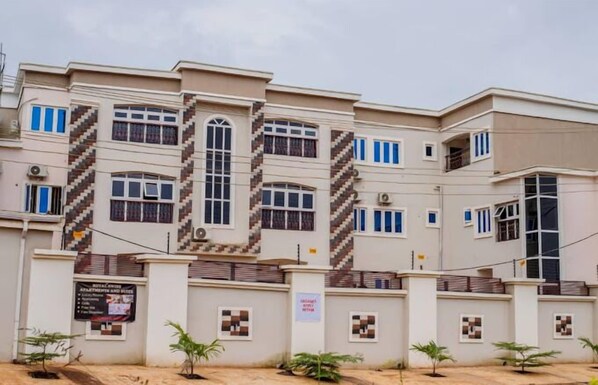 A multi-story building with a symmetrical facade, featuring a central staircase, multiple windows, and a gated entrance. - Royal Swiss Apartments and Suites (Enugu)