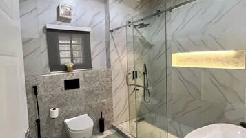 A modern bathroom with a glass-enclosed shower, a white sink, and a marble-patterned floor.